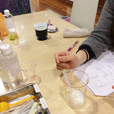 手作り化粧品の作り方を聞いてメモをとっている女性の手元